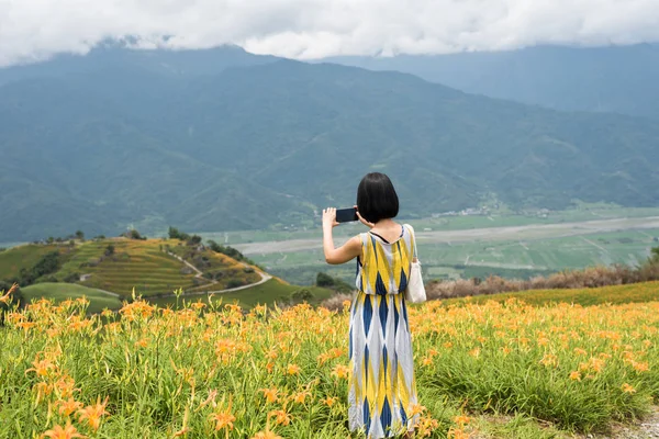 アジアの女性の写真を撮ると黄色のオニユリの農場でスタンド — ストック写真