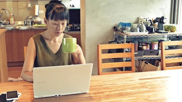 Asyalı olgun kadın dizüstü bilgisayar kullanıyor, evde çalışma kavramı