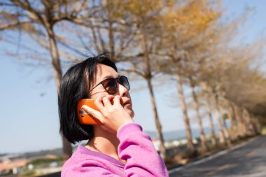 Olgun Asyalı güzellik konuşmaları açık havada cep telefonunda.