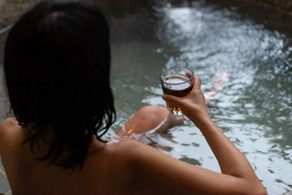 アジア熟女の背面は温泉プールで紅茶のカップを保持します — ストック写真
