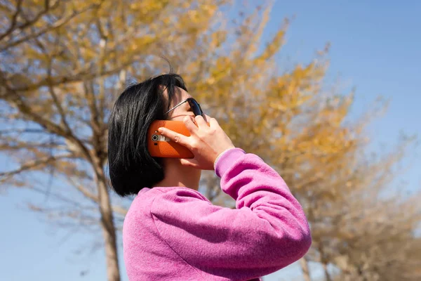 成熟したアジアの美しさは屋外で携帯電話で話す — ストック写真