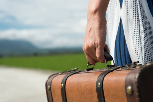woman holding a suitcase on the road in the countryside