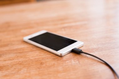 Ahşap masanın üzerinde şarj mobil akıllı telefon