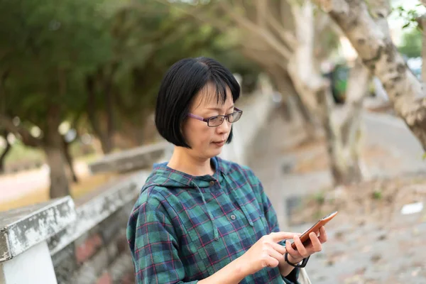 Aziatische volwassen vrouw met behulp van mobiele telefoon — Stockfoto