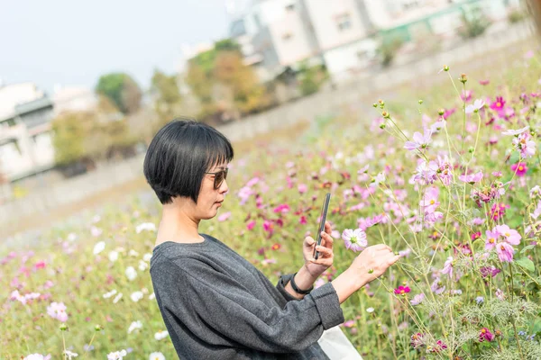 Kvinnan ta en bild på en blomma — Stockfoto