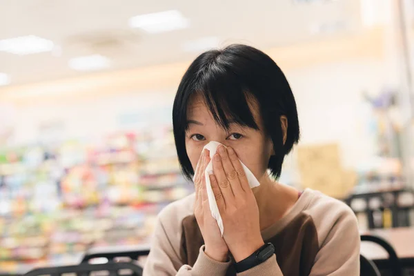 Mujer asiática se siente enferma y estornuda — Foto de Stock