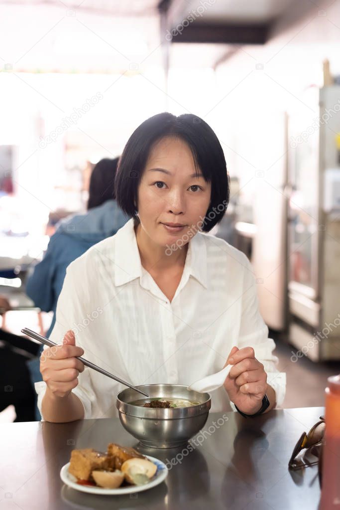 mature Asian woman eat noodles