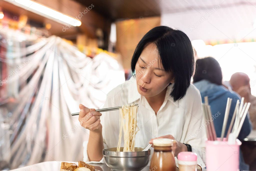mature Asian woman eat noodles
