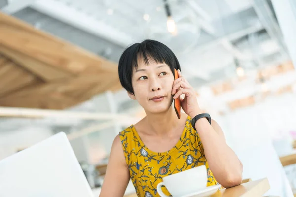 Женщина слушать на мобильный телефон и работать — стоковое фото