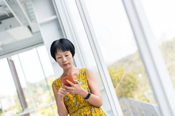 Mulher asiática madura usando celular — Fotografia de Stock