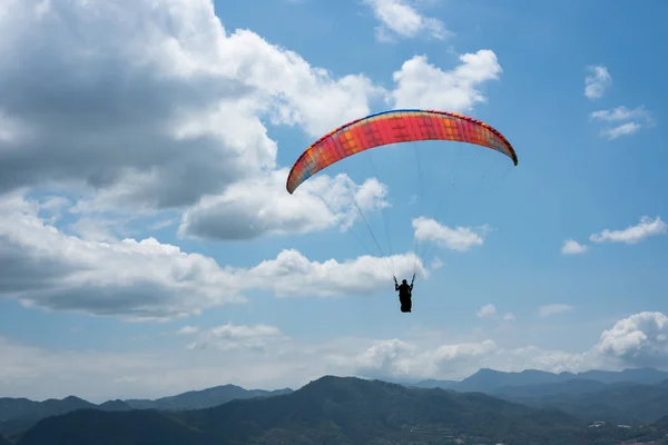 Parapente colorido sob o céu azul — Fotografia de Stock