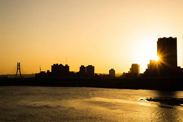 Silhouette von Gebäuden mit Fluss bei Sonnenuntergang — Stockfoto