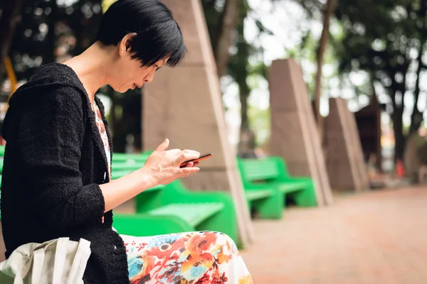 Kvinna sitter och använder mobiltelefon — Stockfoto