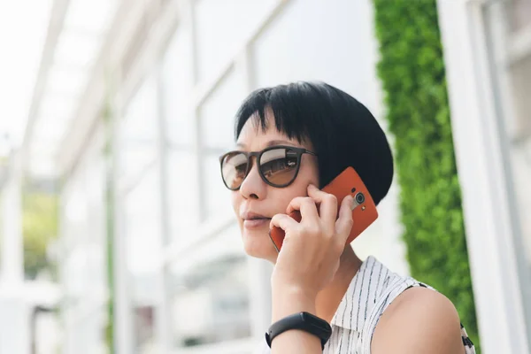 Asyalı kadın oturup cep telefonuyla konuşmak — Stok fotoğraf