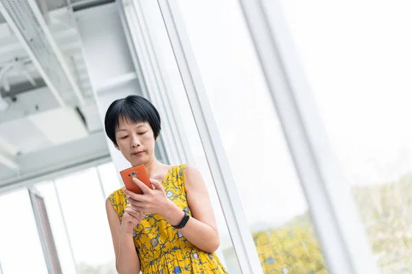Зріла Азіатська жінка за допомогою стільникового телефону — стокове фото