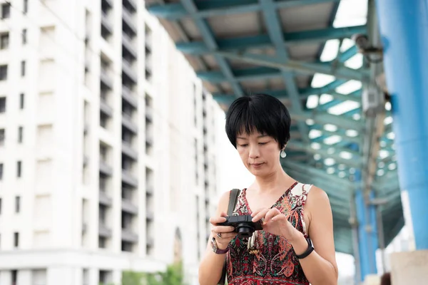 Mature Asian woman using digital camera — Stock Photo, Image