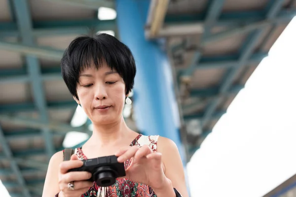 Dojrzały Asian kobieta przy pomocy cyfrowy aparat fotograficzny — Zdjęcie stockowe