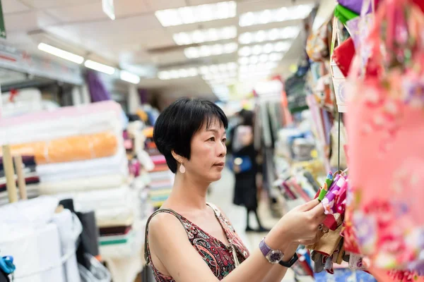 女人在布艺商场里挑一卷布 — 图库照片