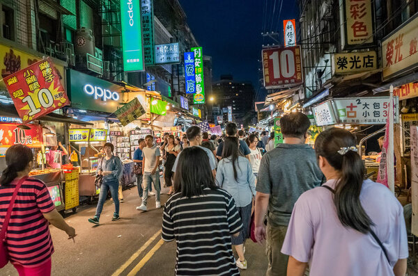 люди ходят и делают покупки на ночном рынке в Тайбэе
