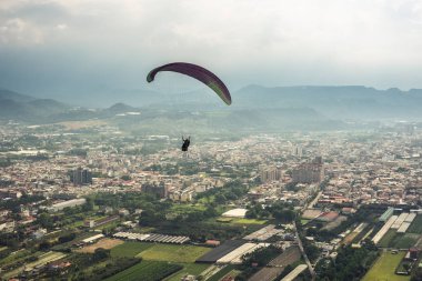 şehirde mavi gökyüzü üzerinde renkli yamaç paraşütü
