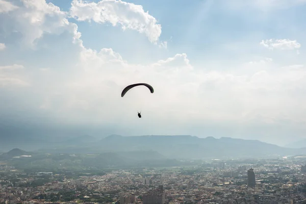 Şehirde mavi gökyüzü üzerinde renkli yamaç paraşütü — Stok fotoğraf