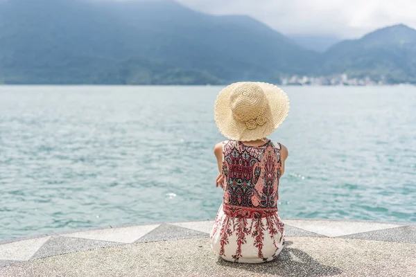 Woman with hat sit at a pier — Stock Photo, Image