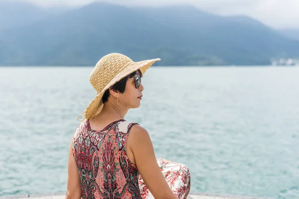 帽子をかぶった女性が桟橋に座る — ストック写真