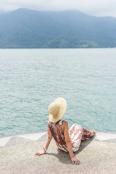 Woman with hat sit at a pier — Stock Photo, Image
