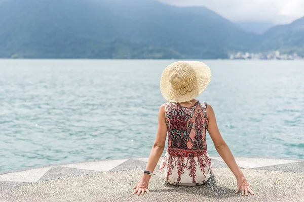 Woman with hat sit at a pier — Stock Photo, Image