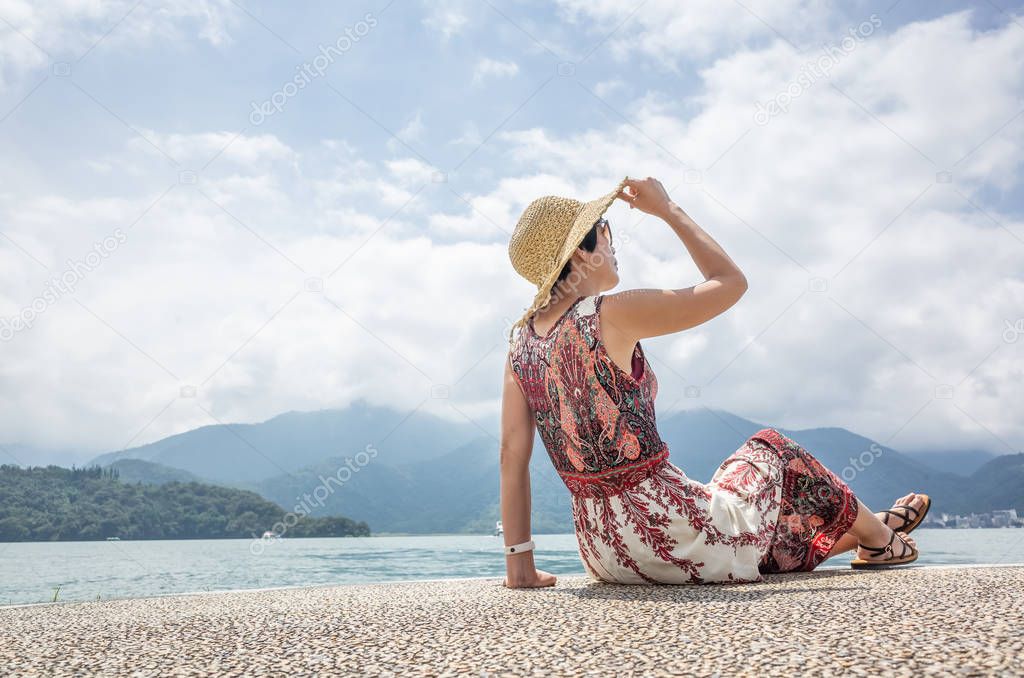 woman with hat sit at a pier