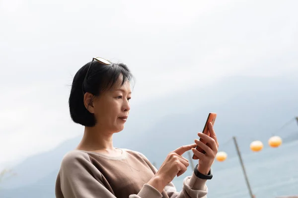 Mulher asiática madura usando telefone móvel — Fotografia de Stock