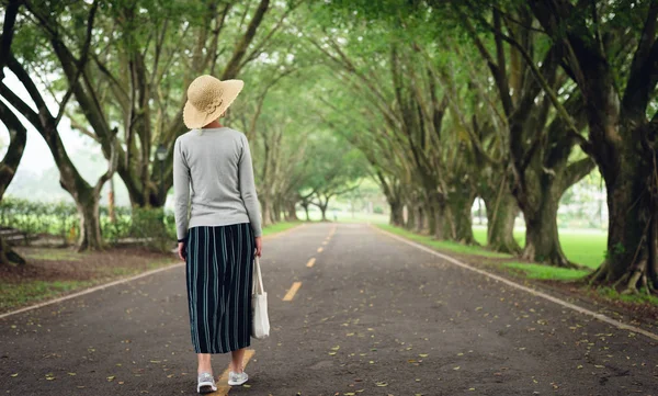 女は木の下で道を歩いていく — ストック写真