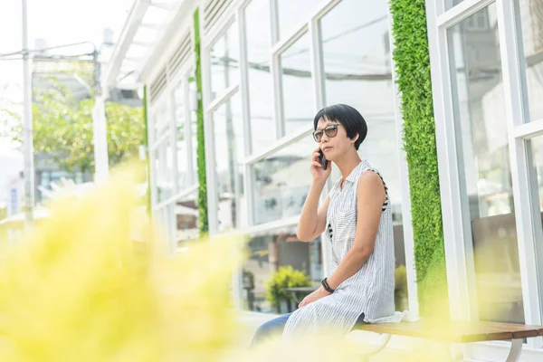 Asian woman sit and talk on cellphone — Stock Photo, Image