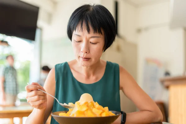 女性はマンゴーのかき氷を食べる — ストック写真