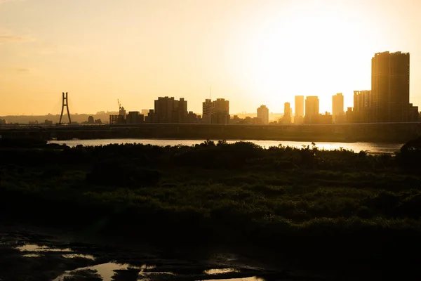 Silhouet van gebouwen met rivier bij zonsondergang — Stockfoto