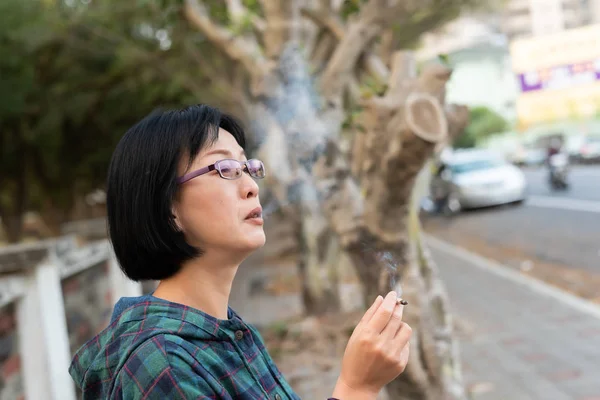 Asian mature woman smoking — Stock Photo, Image
