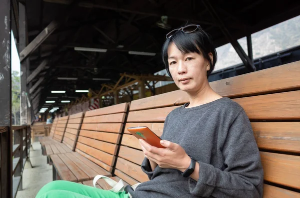 Frau sitzt auf Stuhl und benutzt Smartphone — Stockfoto