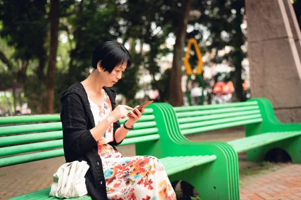Kobieta siedzi i za pomocą telefonu komórkowego — Zdjęcie stockowe