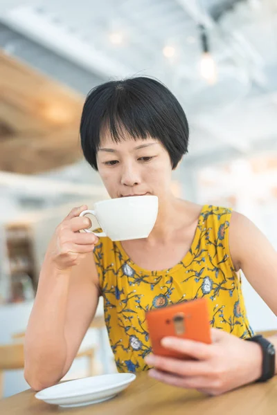 Γυναίκα που χρησιμοποιεί κινητό τηλέφωνο σε μια καφετέρια — Φωτογραφία Αρχείου