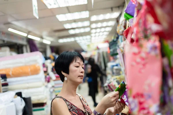 女人在布艺商场里挑一卷布 — 图库照片