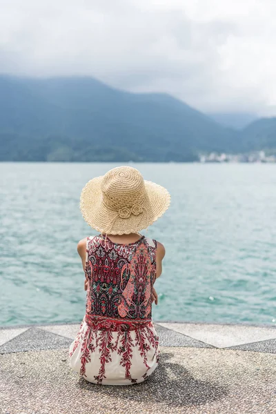 Mulher com chapéu sentar em um cais — Fotografia de Stock