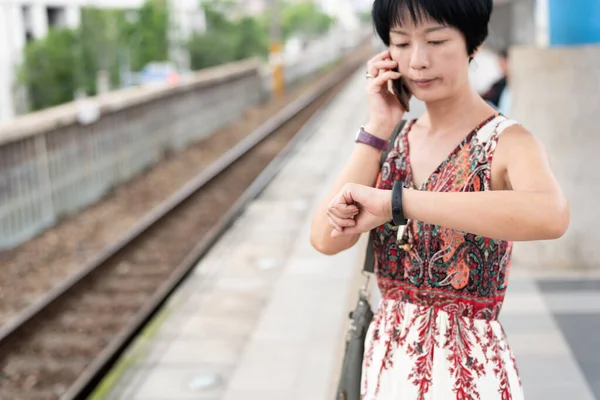 Vrouw praten op mobiele telefoon en kijk haar horloge — Stockfoto