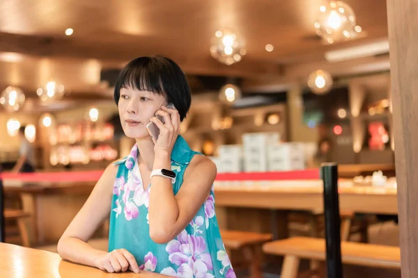 mature Asian woman talk on cellphone at a coffee shop