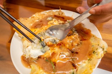 Kadınlar geleneksel Tayvan usulü istiridye omleti yerler.