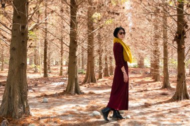 modern Asyalı olgun kadın ormanda yürüyor.