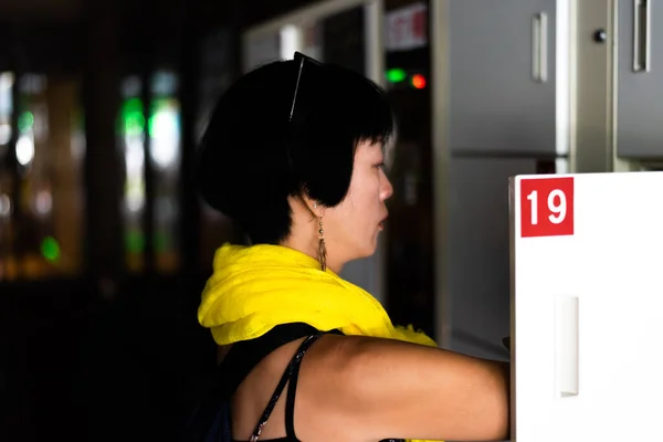 アジア系の女性が駅にロッカーを開けて — ストック写真
