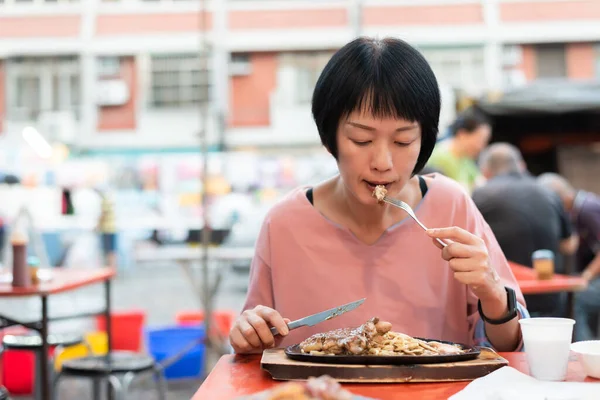 成熟女人在街上吃台湾夜市牛排 — 图库照片