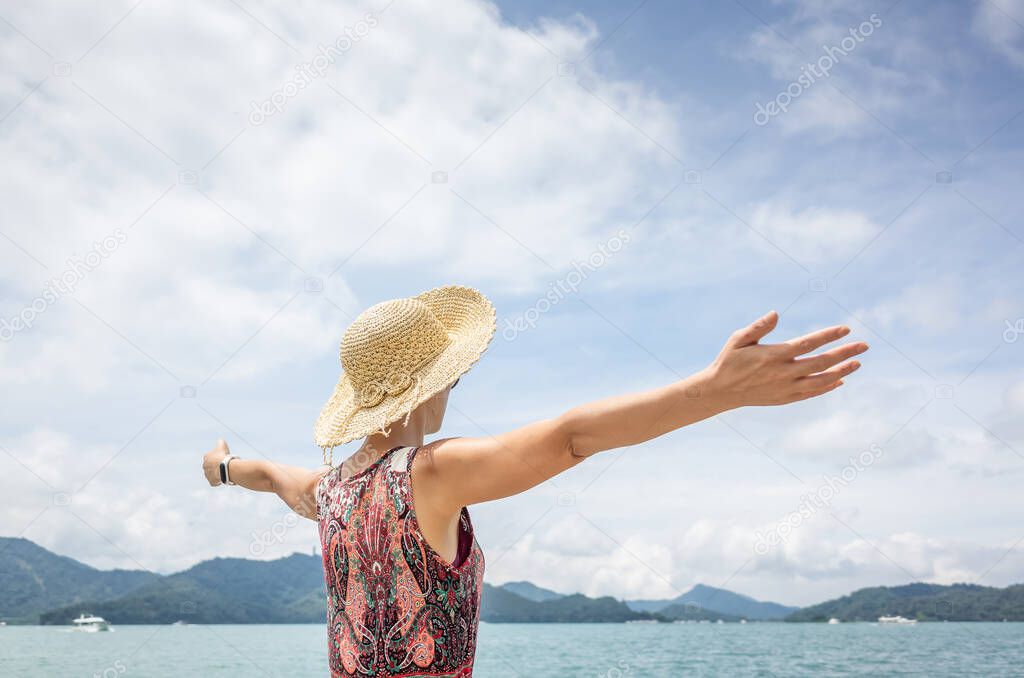 traveling Asian woman with hat open arms at Sun Moon Lake, Taiwan