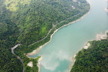 Mingtan Reservoir, Shuili kasabası, Nantou, Tayvan 'daki göl kenarındaki ağaçların olduğu bir yol manzarası.