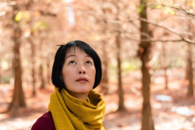 Modern Asyalı olgun bir kadının ormandaki yakın plan portresi.